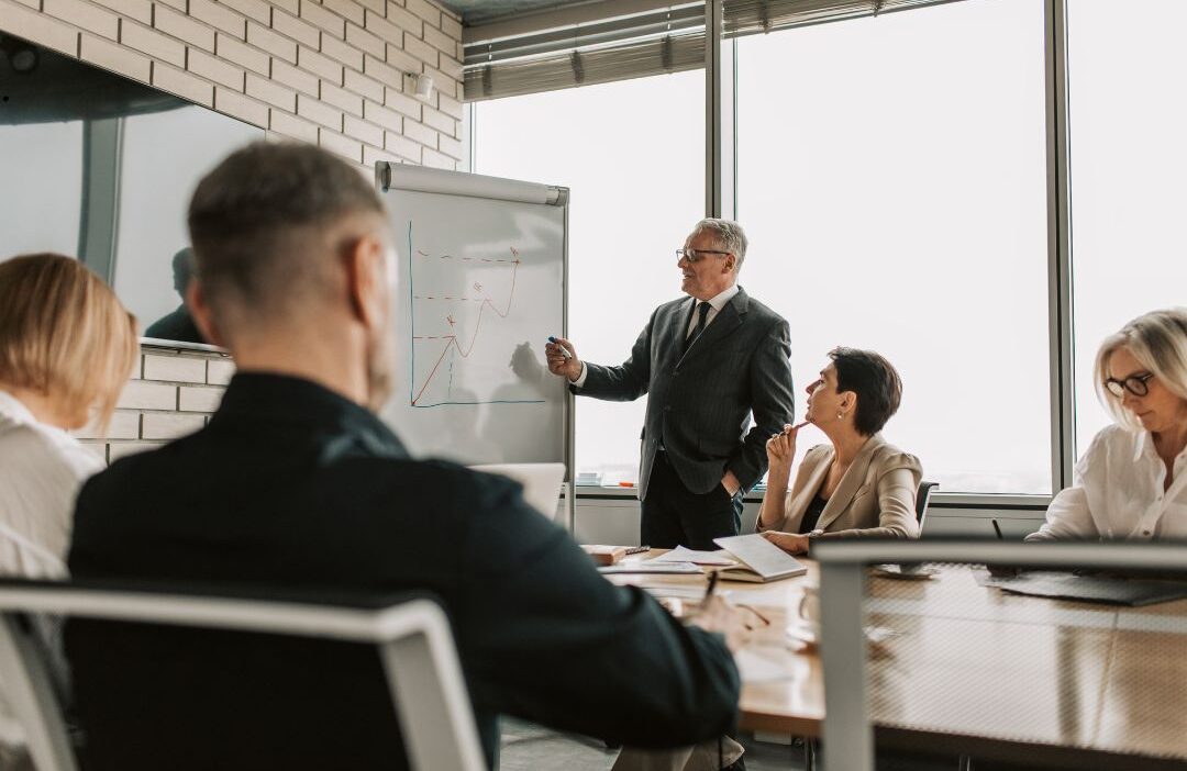 Executive team reviewing financial hiring data and cost comparisons during a strategy meeting